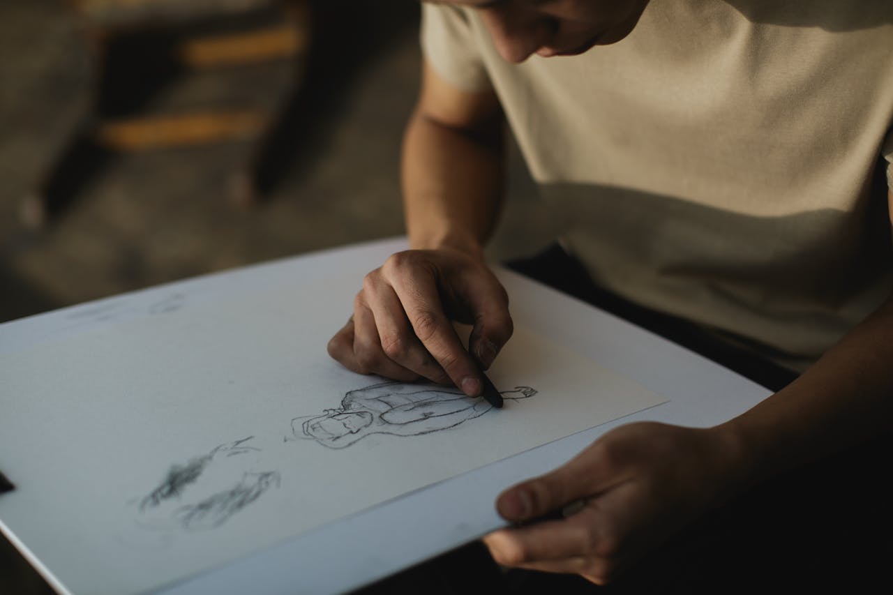 Close-up of a person sketching on paper with concentrated focus indoors.